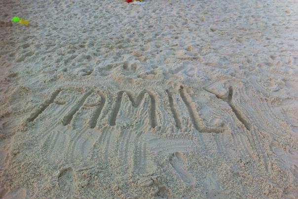 "Family" written in sand on the beach.