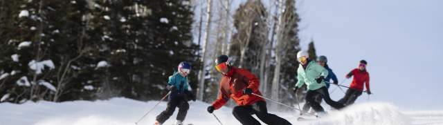 Family skiing down groomer run