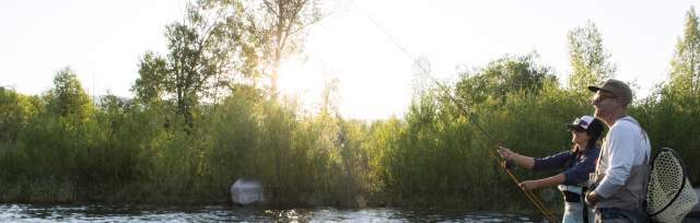 Man and woman fly fishing in the summer on the Provo River.