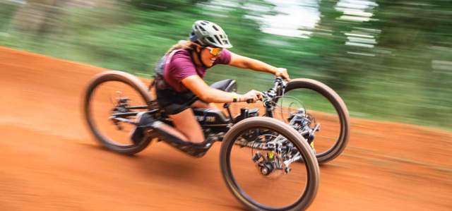 An adaptive biker rides a trail through green woods in Park City, UT