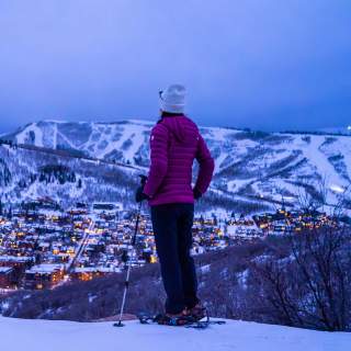 A snowshoer gazes over Park City at dusk in the winter