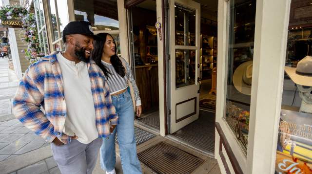 A couple smiles while looking at merchandise through a store window on Historic Main Street, Park City, UT.
