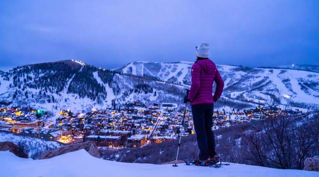 A snowshoer gazes over Park City at dusk in the winter