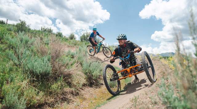An adaptive mountain biker rides on a wide trail in Round Valley in Park City, UT