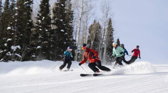Family skiing down groomer run