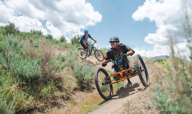 An adaptive mountain biker rides on a wide trail in Round Valley in Park City, UT