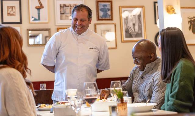 A chef laughs and talks with patrons at a restaurant in Park City, UT