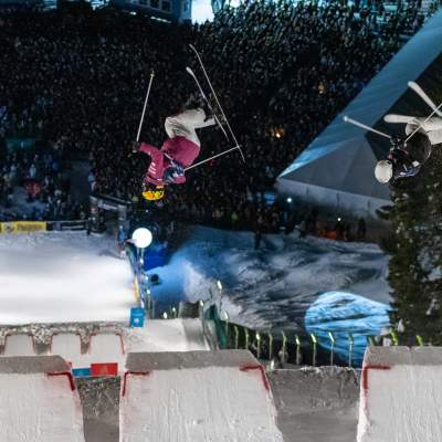 Two skiers perform aerial tricks in the dual moguls competition at night at Deer Valley in Park City, UT