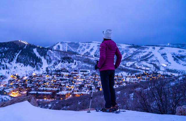 A snowshoer gazes over Park City at dusk in the winter
