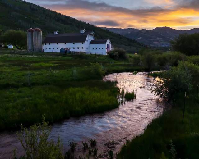 The McPolin Barn beyond a stream at sunset in Park City, UT