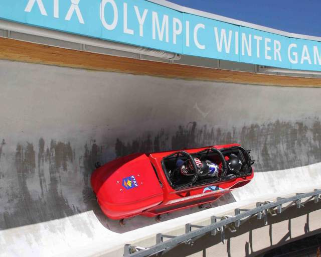 A group of four people ride in a bobsled in the summer on the bobsled track at the Utah Olympic Park in Park City, UT