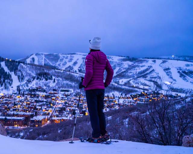 A snowshoer gazes over Park City at dusk in the winter