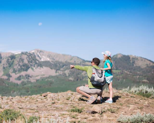 Father and young daughter looking at view from top of mountain