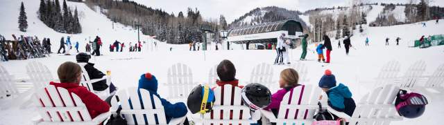 A family relaxes on white adirondack chairs at the Silver Lake ski beach in Park City, UT