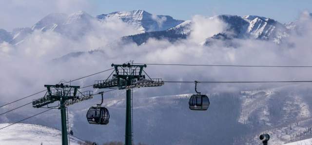 Deer Valley gondola cabins cross in front of a mountain landscape shrowded in low lying clouds