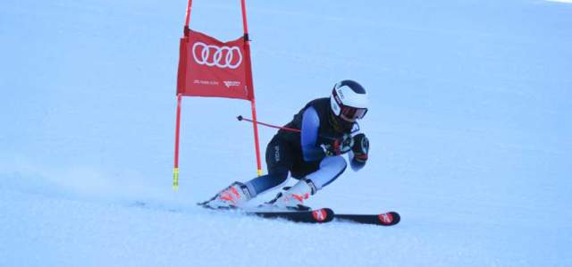A ski racer carves a turn around a gate on a ski run at the Utah Olympic Park in Park City, UT
