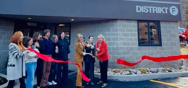A group of people celebrate a ribbon cutting event in front of the Distrikt F location in Park City, UT