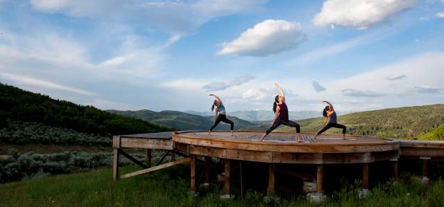 Three women do yoga on a yurt pad at Bluesky near Park City, UT
