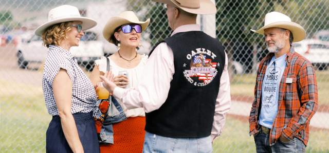 Four people network and enjoy drinks on a lawn at the Oakley Rodeo in Summit County, UT
