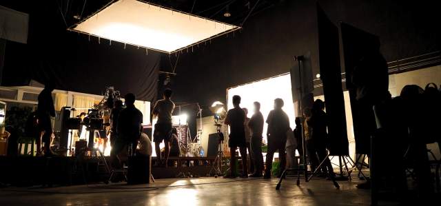 A film production crew works on a  set with lighting and cameras