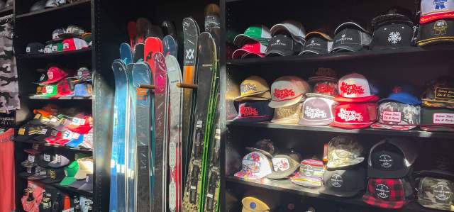 Inside view of Silver Star Ski and Sport displaying shelves of baseball caps alongside skis and snowboards.