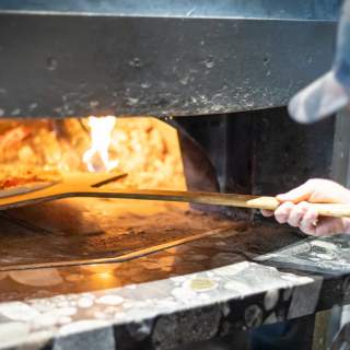 A cook slides a pizza into a wood fired oven at Loma in Park City, UT