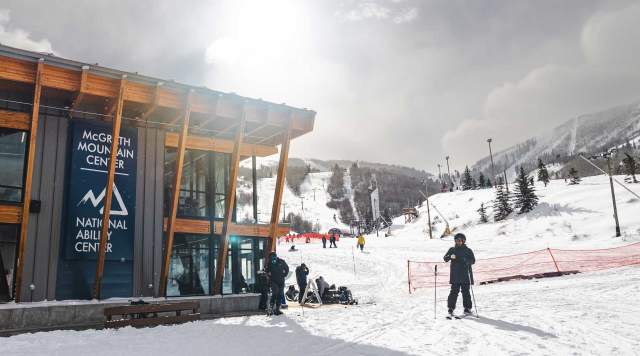 A skier and other stand outside the McGrath Mountain Center at Park City Mountain on a snowy day