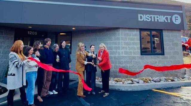 A group of people celebrate a ribbon cutting event in front of the Distrikt F location in Park City, UT