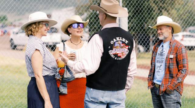 Four people network and enjoy drinks on a lawn at the Oakley Rodeo in Summit County, UT