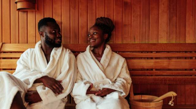 Two people in robes smile at each other while sitting in a sauna in a spa in Park City, UT