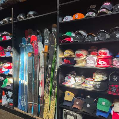 Inside view of Silver Star Ski and Sport displaying shelves of baseball caps alongside skis and snowboards.
