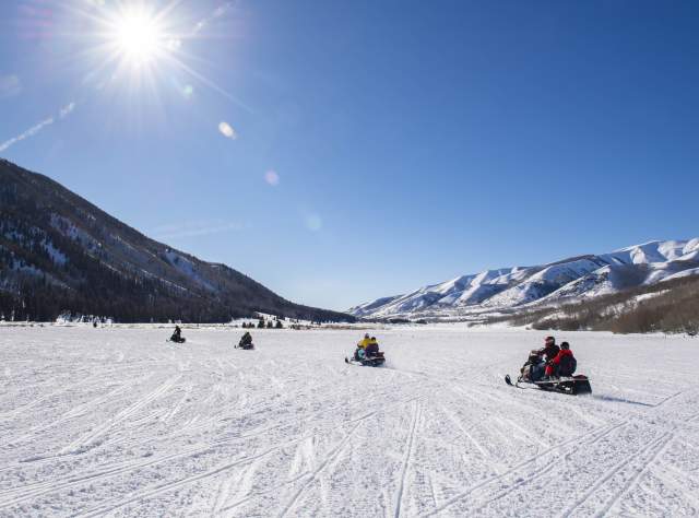 Group of snowmobiles in a wide-open field in Weber Canyon on sunny day.