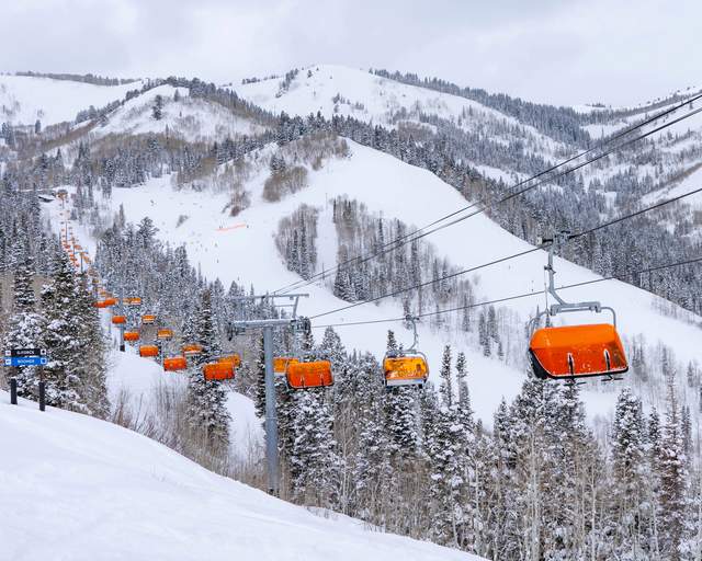The Orange Bubble chairlift crosses over a snowy run and trees at Park City Mountain