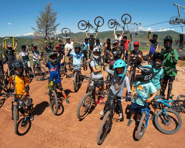 A group of kids celebrate after a mountain bike camp on a trail at Woodward in Park City