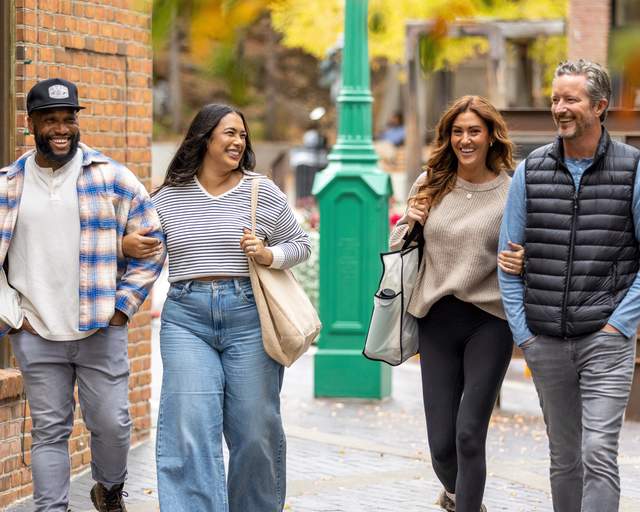 Two couples laugh and talk while walking on Historic Main Street in Park City, UT