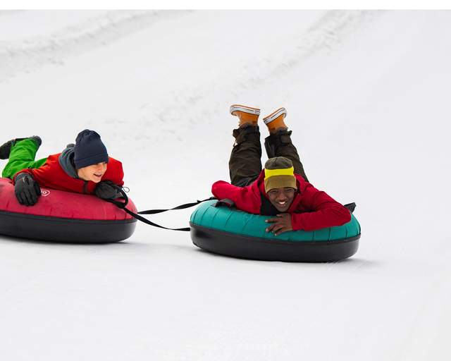 Two young boys ride inflatable tubes on a tubing hill at Woodward in Park City, UT