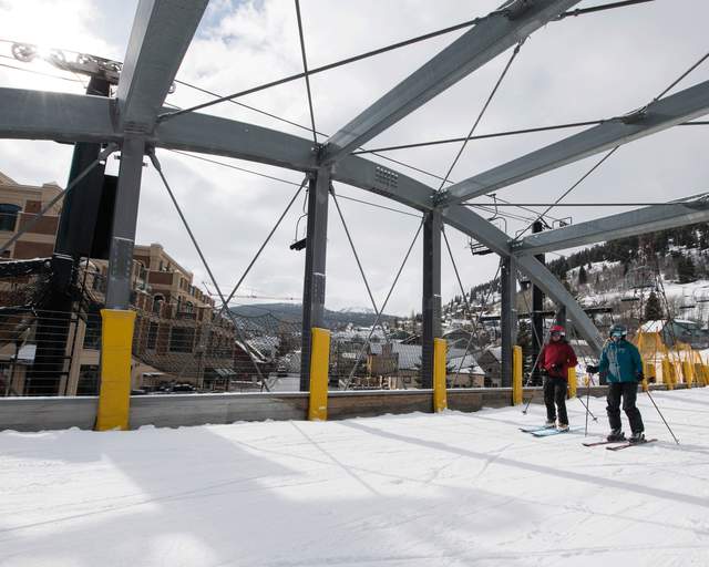 Two skiers ski over a bridge underneath the Town Lift in Park City, UT