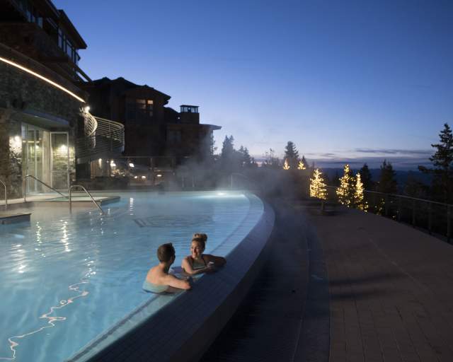 Poolside view of a couple enjoying the sunset in an infinity pool.