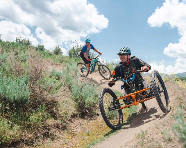 An adaptive mountain biker rides on a wide trail in Round Valley in Park City, UT