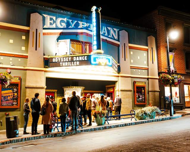 The Egyptian Theatre lit up at night with a queue of people outside in Park City, UT