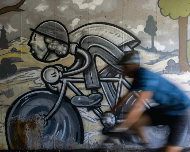 A cyclist rides by a mural of a bike rider in a tunnel in Park City, UT. Photo by Mark Maziarz.