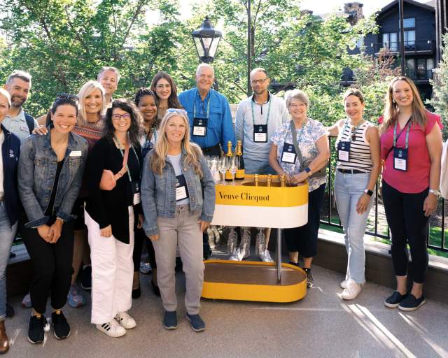 A group of people pose for a photo on a patio on sunny summer day in Park City, UT