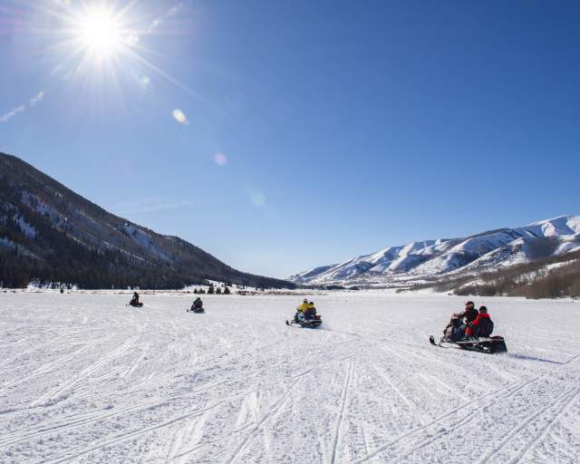 Group of snowmobiles in a wide-open field in Weber Canyon on sunny day.