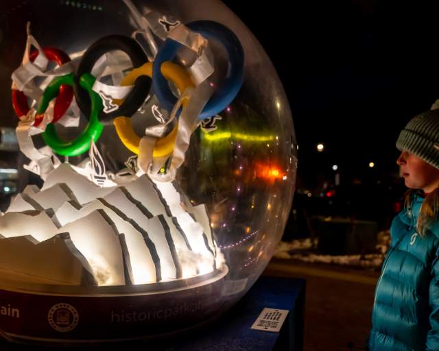 A young girl stares into a snow globe art installation on Main Street in Park City, UT
