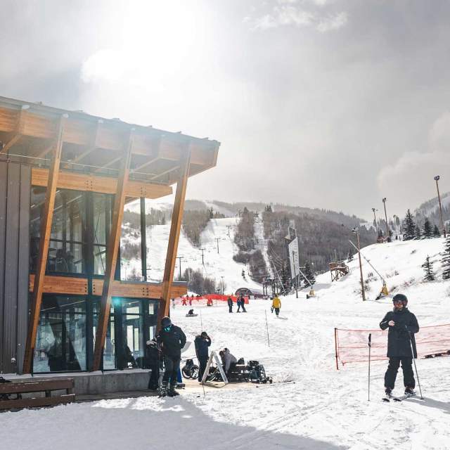 A skier and other stand outside the McGrath Mountain Center at Park City Mountain on a snowy day