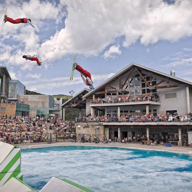 Performers on skis jump into a pool during a Flying Aces show on a cloudy summer day at the Utah Olympic Park in Park City, UT