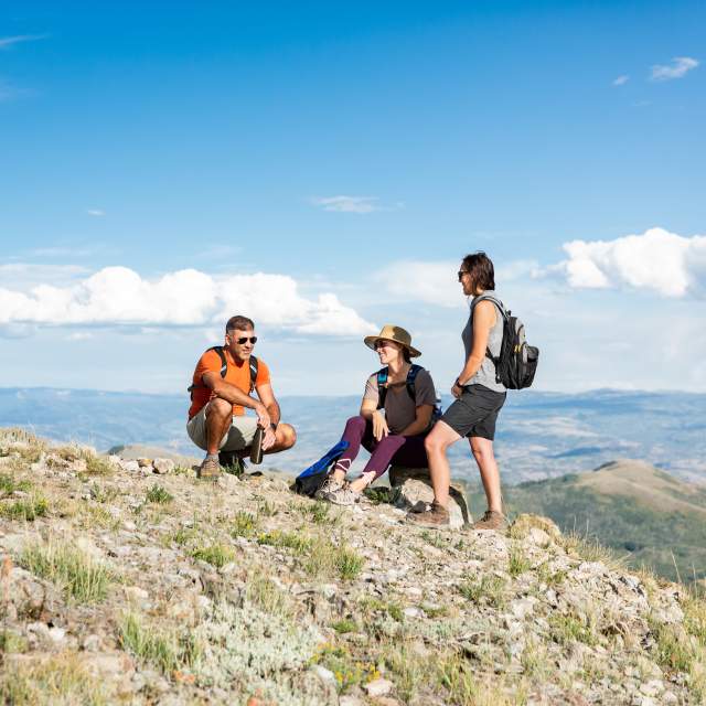 three hikers resting at the top of the mountain