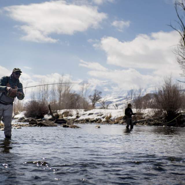 Two people fly fishing in the winter