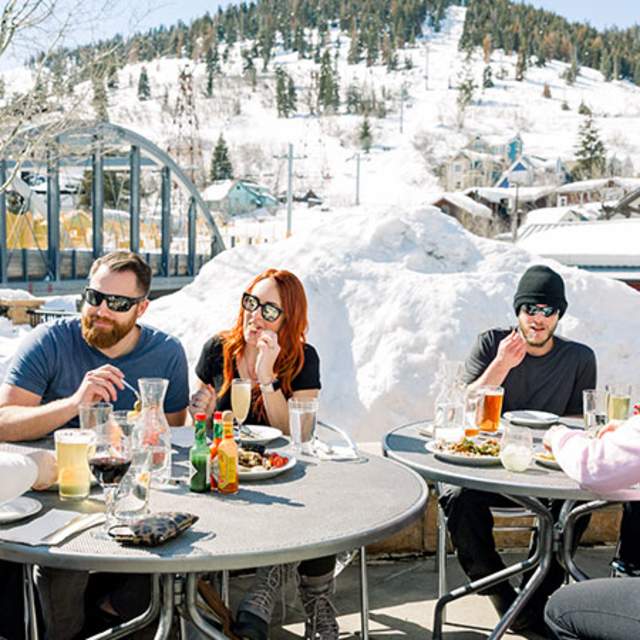 Two tables of adults enjoying lunch on the patio of The Bridge Care on a sunny winter day.