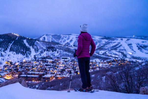 A snowshoer gazes over Park City at dusk in the winter